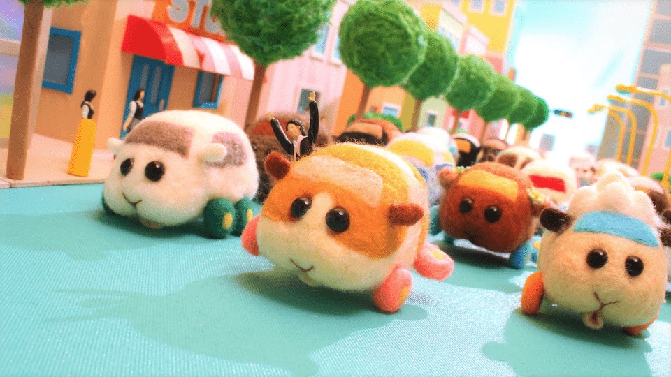 A stampede of felt guinea pig car plushies driving down the street.