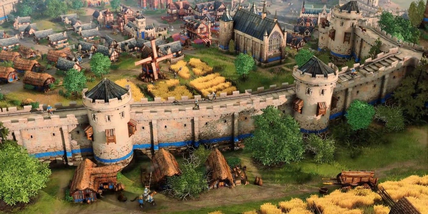 Screenshot from Age of Empires. A medieval city with stone walls, a windmill, and a church.