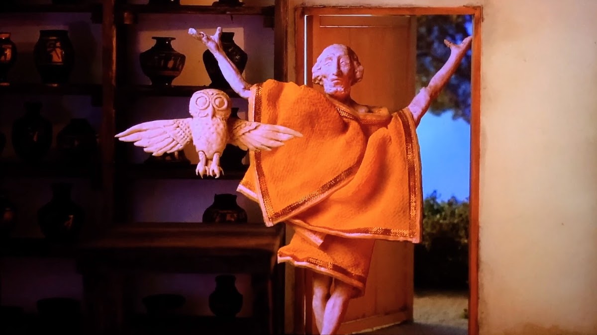 Stop-motion shot from Extra Olympia Kyklos of a man wearing a toga and an owl.