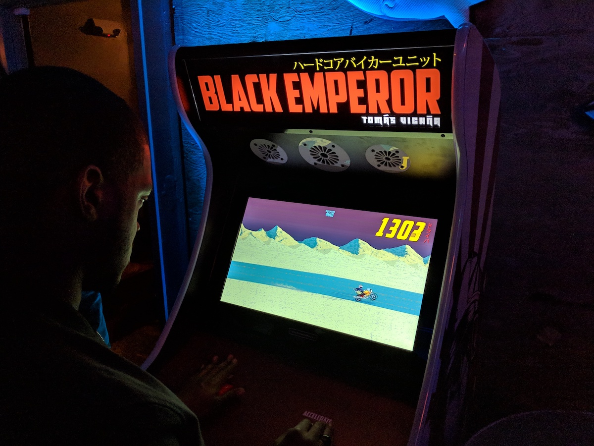 Arcade cabinet for Black Emperor in a dark room. A man is standing in front of it, playing the game.