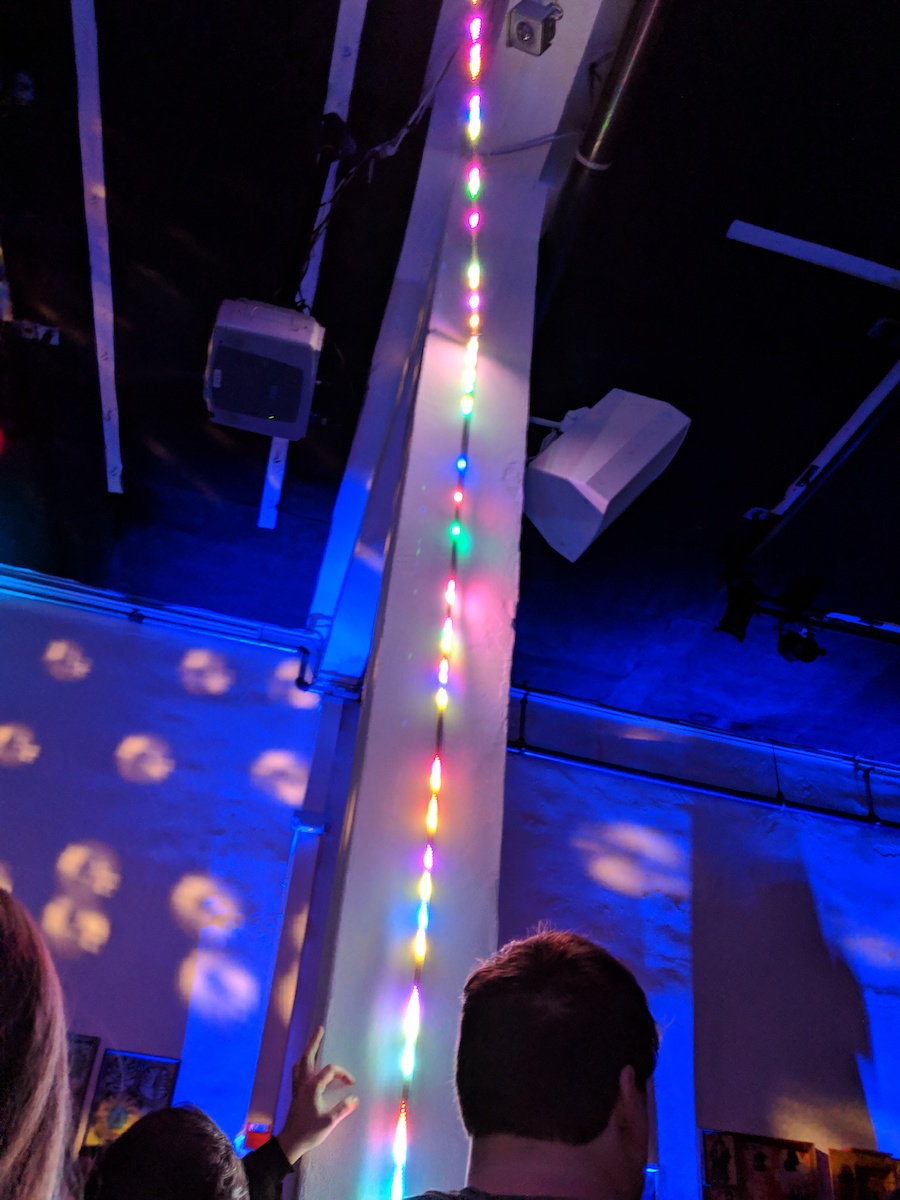 A multicolored LED strip running up the wall in a bar.