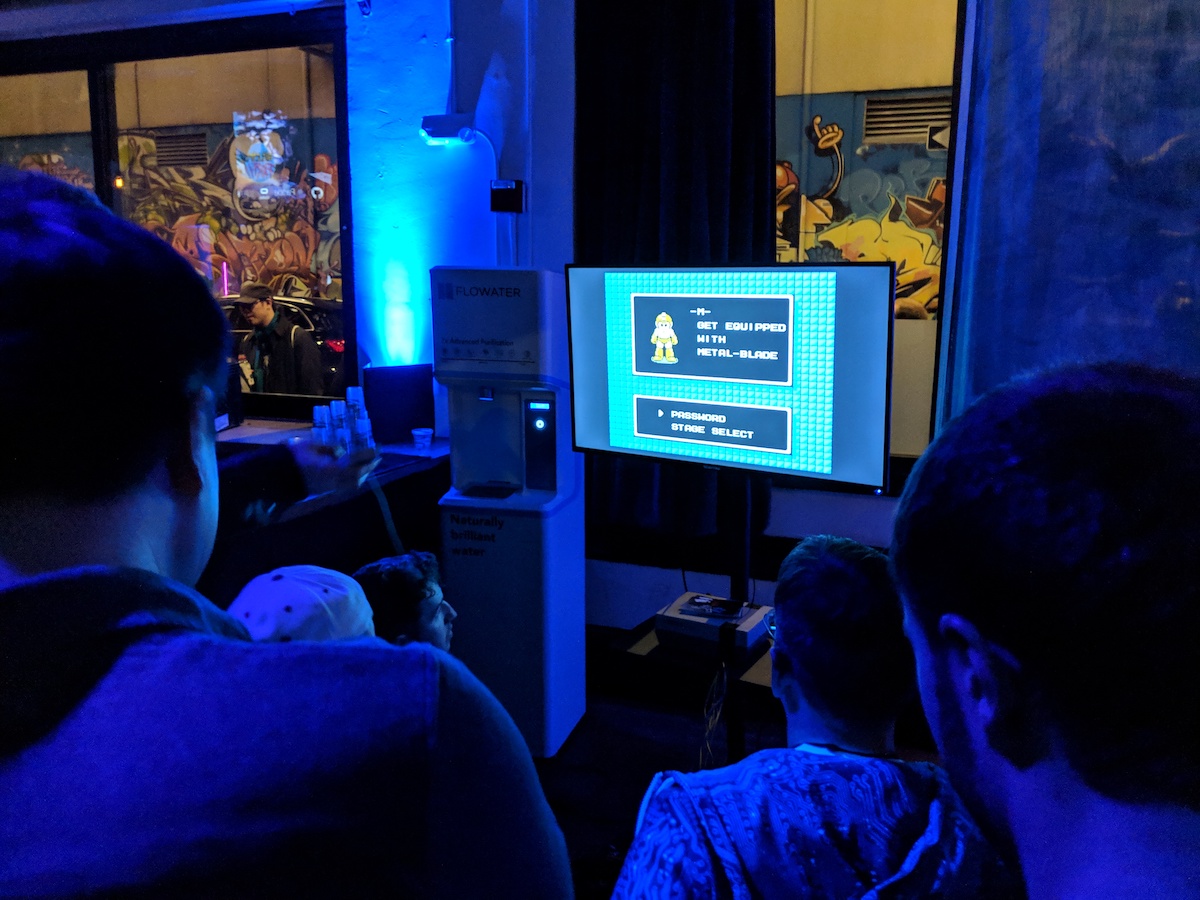A group of people sitting around a TV with Megaman on it.