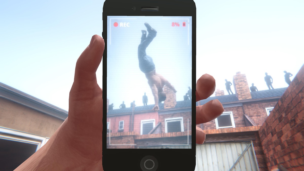 A shirtless young man flipping in the air while being recorded by a cell phone.