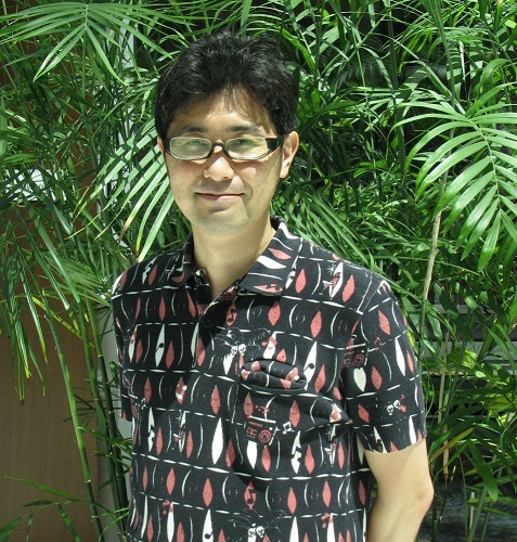 Yoshiaki Kyougoku, a thin middle-aged Japanese man in a button-down shirt, smiling.
