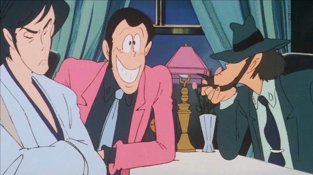 Goemon, Lupin, and Jigen are seated at a table in the dining car of a train. Lupin is grinning while the other two scowl.