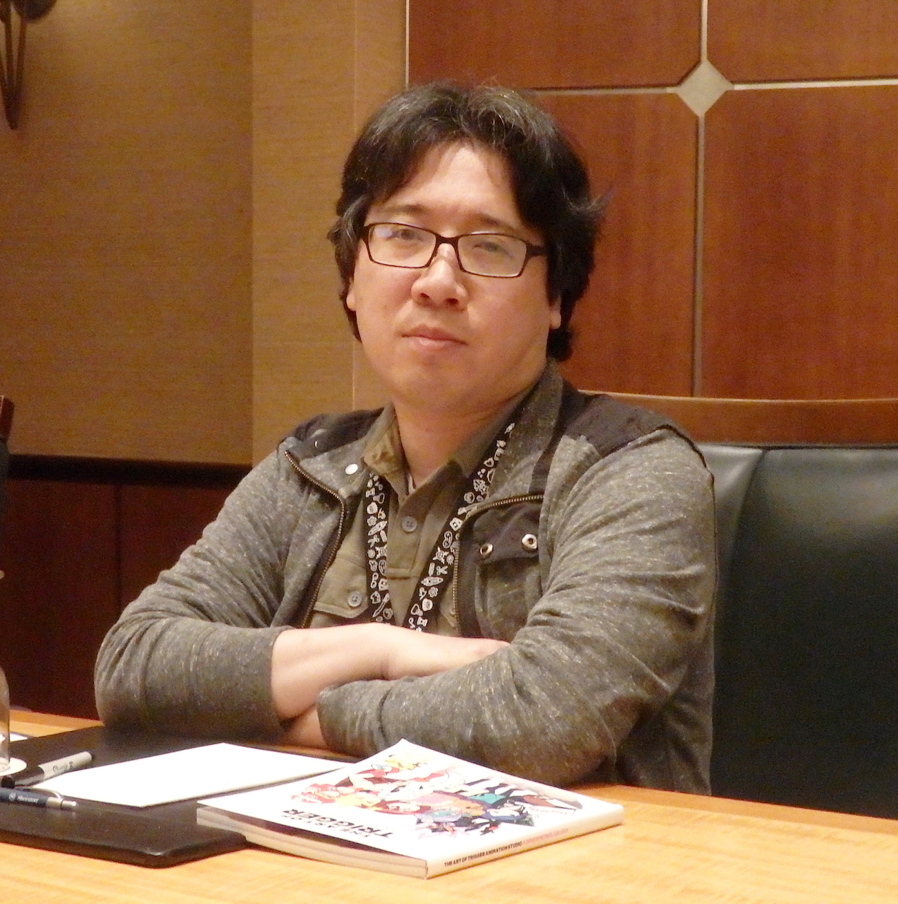 Yoshinari sitting at a table with his arms crossed.